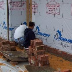 Workers start laying the brick for the front facade of the building.